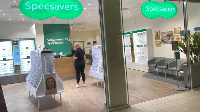 innendørs butikk med dame i sort og grønne skilt