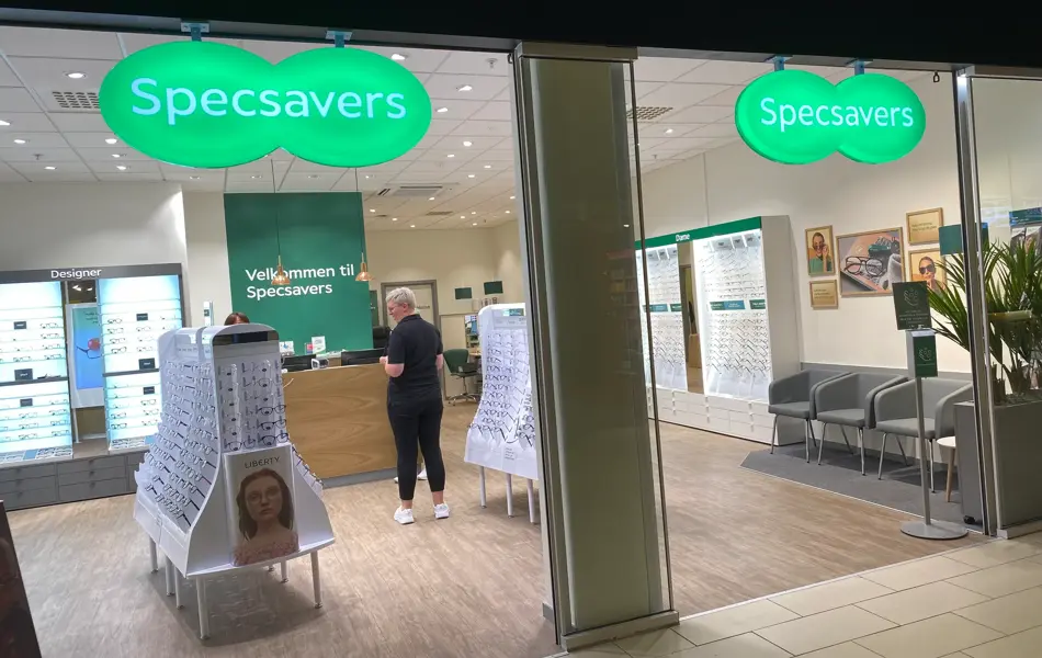 innendørs butikk med dame i sort og grønne skilt