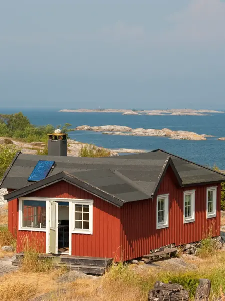 Rød hytte ved kysten, havet, svaberg, sommer.
