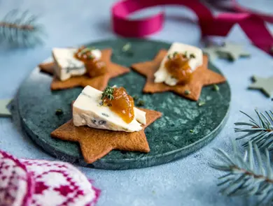 Stjerneformede pepperkaker på et fat med blåmuggost og syltetøy på toppen