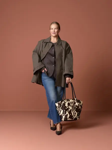 Elen med grønn jakke og topp, jeans, dyremønstret veske og pumps.