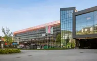 Eksteriørbilde av Thon Senter Vestkanten med næringslokaler, butikk og parkering.