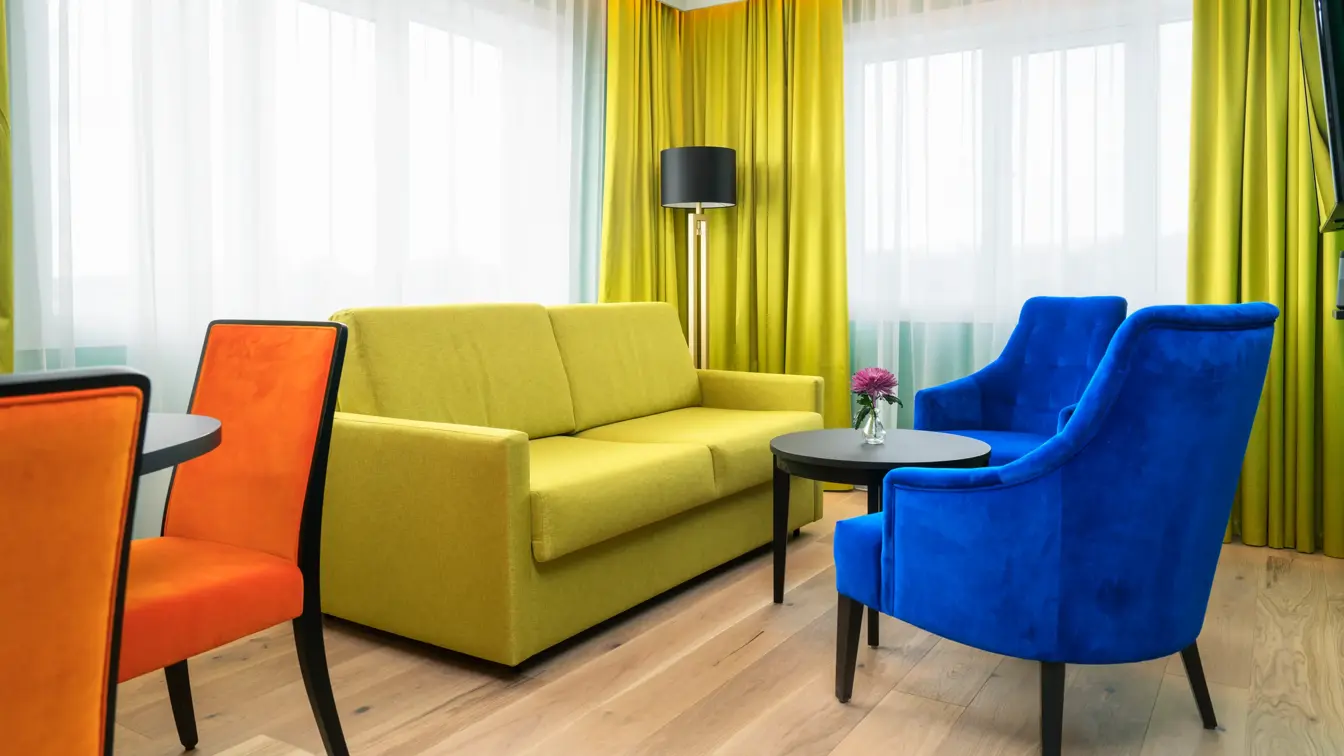 Gul sofa med lenestoler i forskjellige farger på suite Thon Hotel Europa i Oslo sentrum rett ved Slottsparken