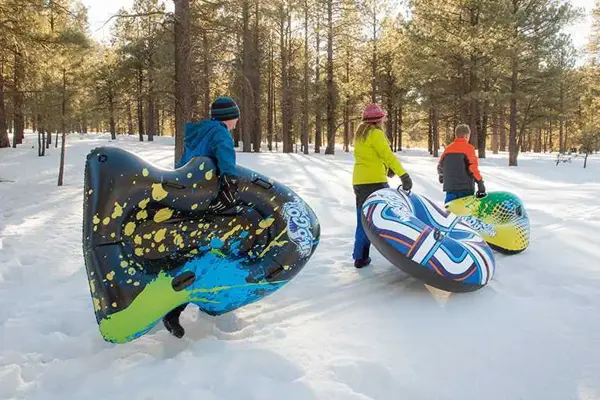 Tre personer som går ute med akebrett under armen