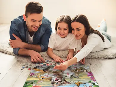Familie legger puslespill med kattemotiv på gulvet.
