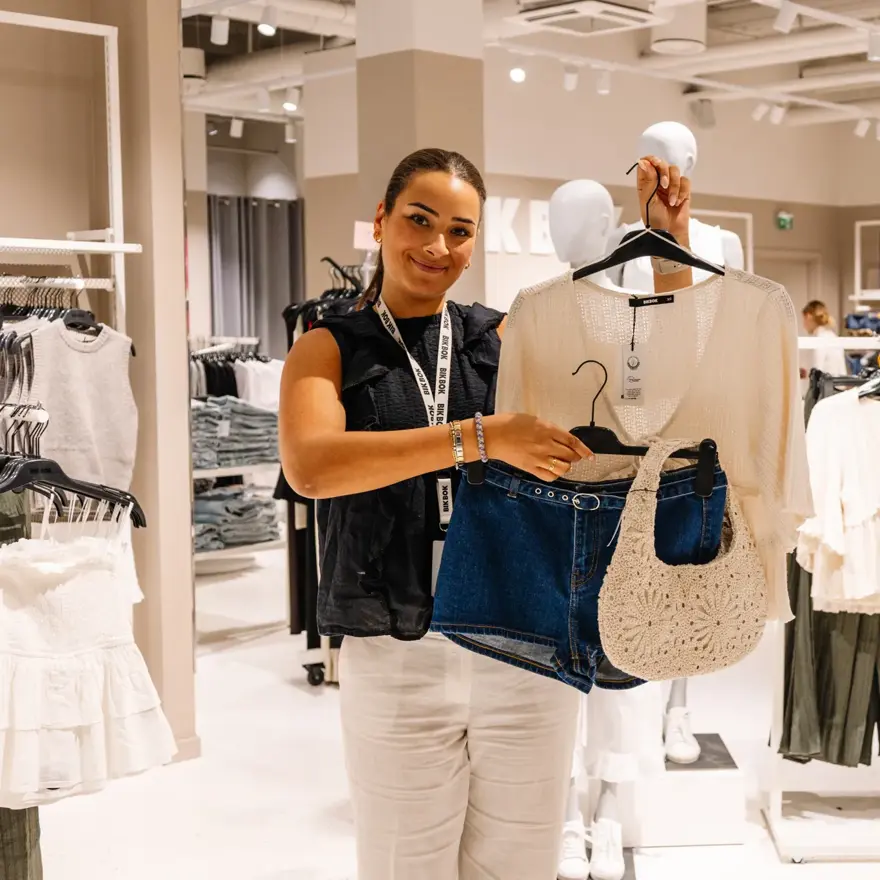 dame holder klær i butikk