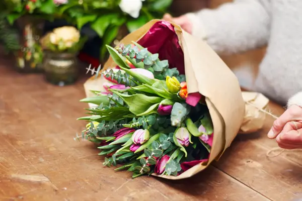 Cropped shot of a pretty floral bouquet being completed on a wooden counter top
