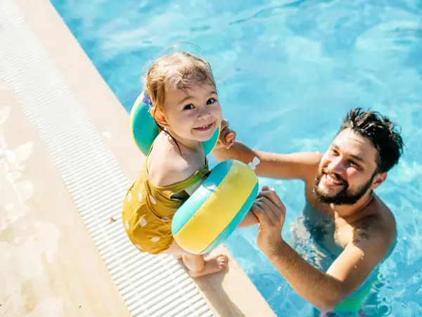 Cute little girl having fun with parents in pool