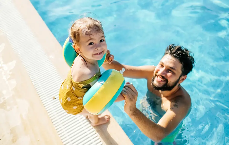 Cute little girl having fun with parents in pool