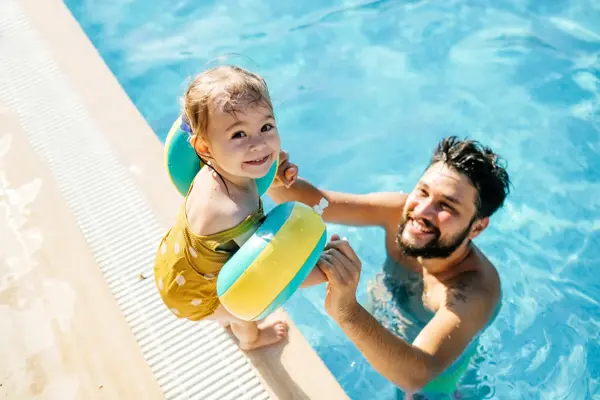 Cute little girl having fun with parents in pool