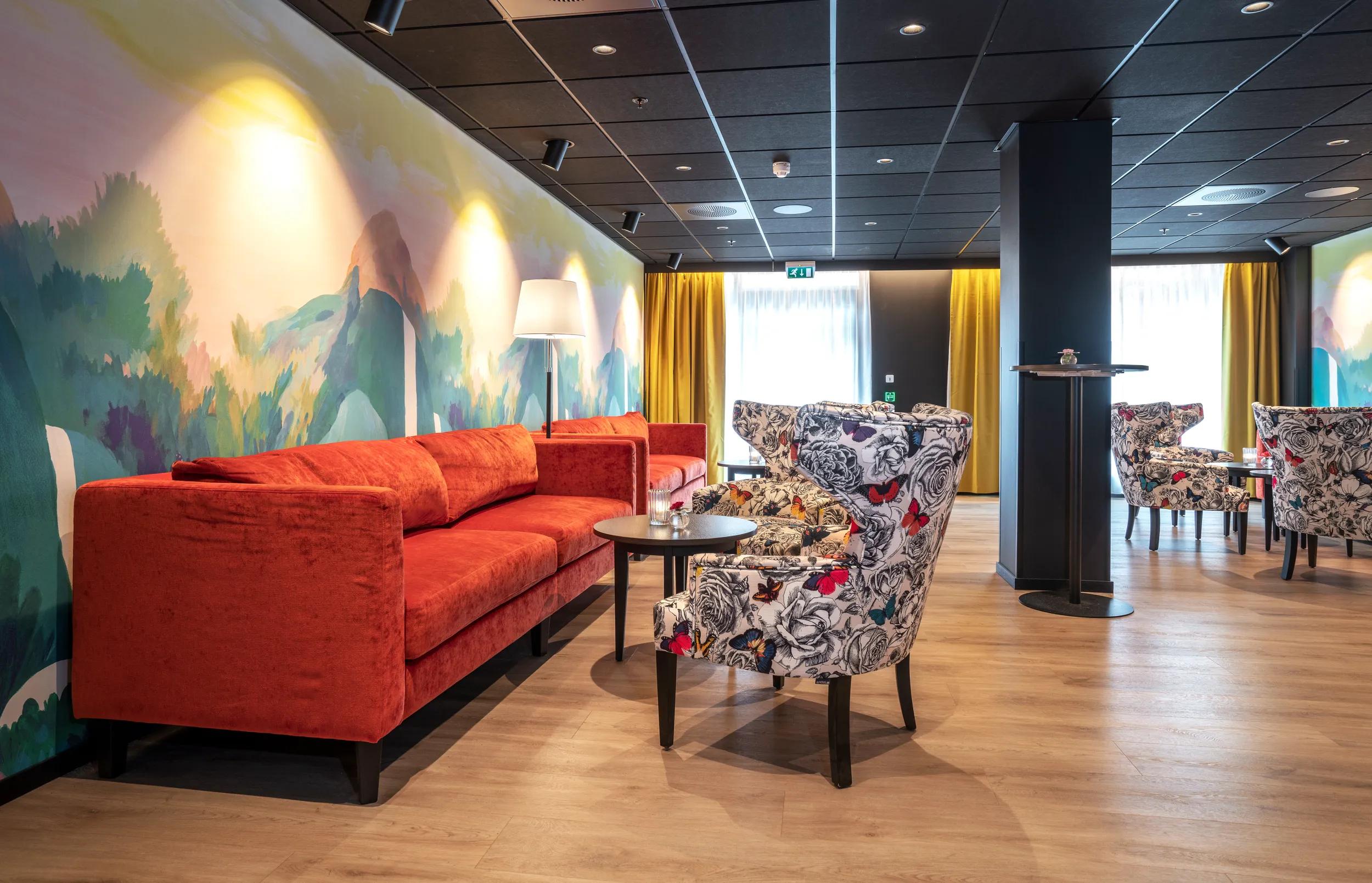 Tapetbilde med isbjørn på veggen over sengen, turkise vegger, store vinduer, dobbeltseng, sittegruppe med to stoler og bord, skrivebord med stol i dobbeltrom på Thon Hotel Polar i Tromsø.