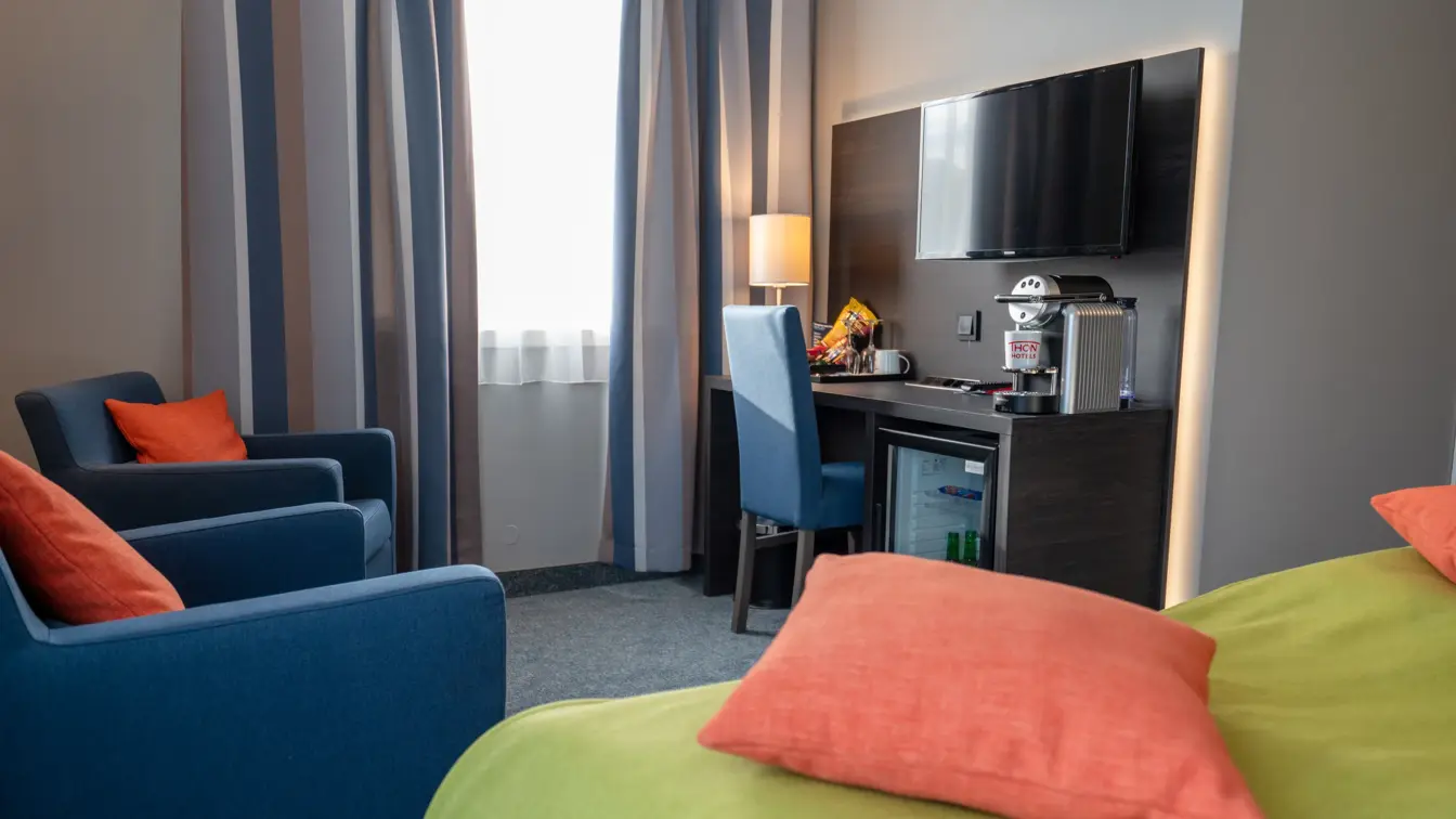 To blå lenestoler, dobbeltseng, skrivebord, stol, vindu, TV