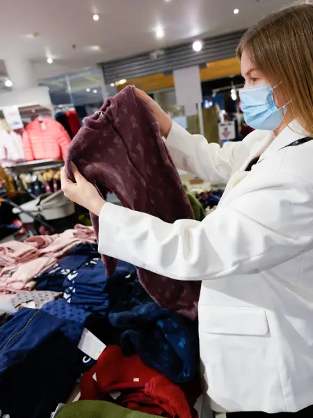 Jente i hvit dressjakke som ser på burgunder ulltøy til barn