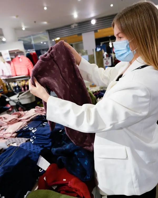 Jente i hvit dressjakke som ser på burgunder ulltøy til barn