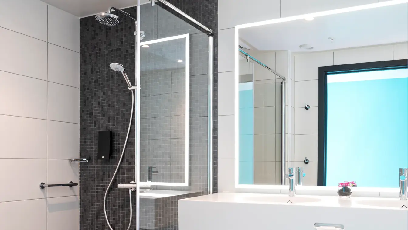 Stor åpen dusj med god gulvplass og lysegrå fliser på gulvet på badet i business og handikaprom på Thon Hotel Storo i Oslo