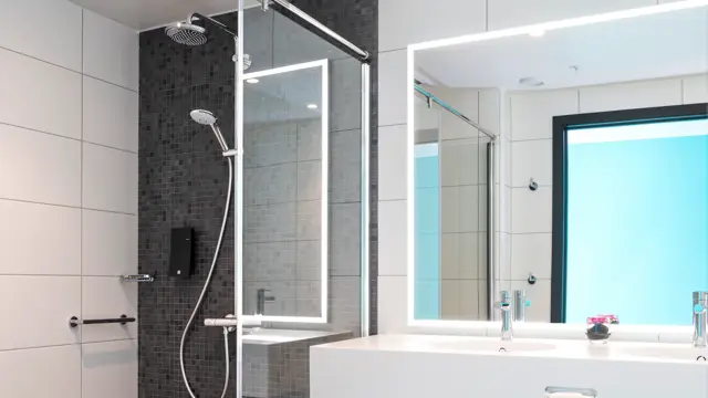 Stor åpen dusj med god gulvplass og lysegrå fliser på gulvet på badet i business og handikaprom på Thon Hotel Storo i Oslo