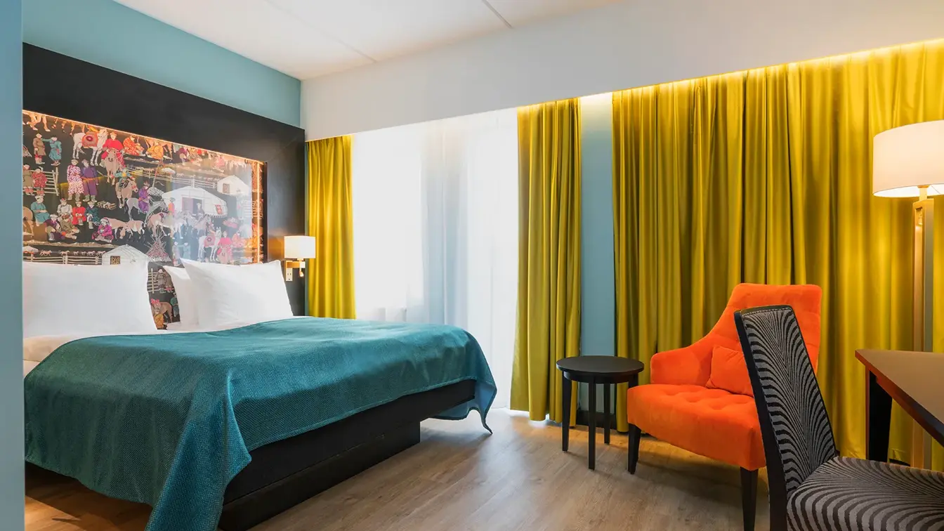 Dobbeltseng, orange lenestol og skrivebord i dobeltrom på Thon Hotel Linne