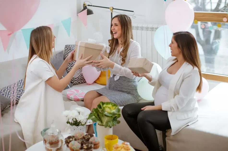 Three cheerful pregnant women exchanging gifts on baby shower