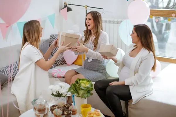 Three cheerful pregnant women exchanging gifts on baby shower