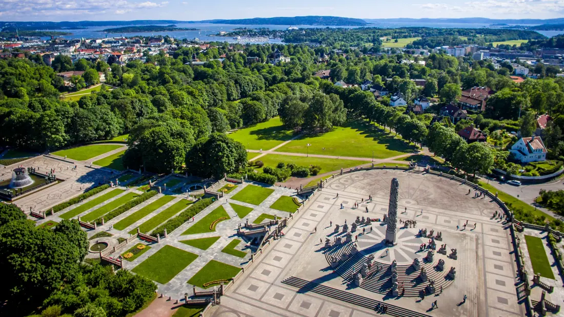 Monolith Statue photographed from the air, using a drone. 
In the horizon the Inner Oslofjord can be seen and the clear blue sky of June is in the background.

Monolith is a stone statue placed on "Monolith Plateau" in Vigeland Park in Oslo.  It consists of 121 figures. The sculpture is surrounded by a circular staircase with 36 groups of figures in granite arranged in rows up the stairs. The sculpture is carved out of a single granite block.