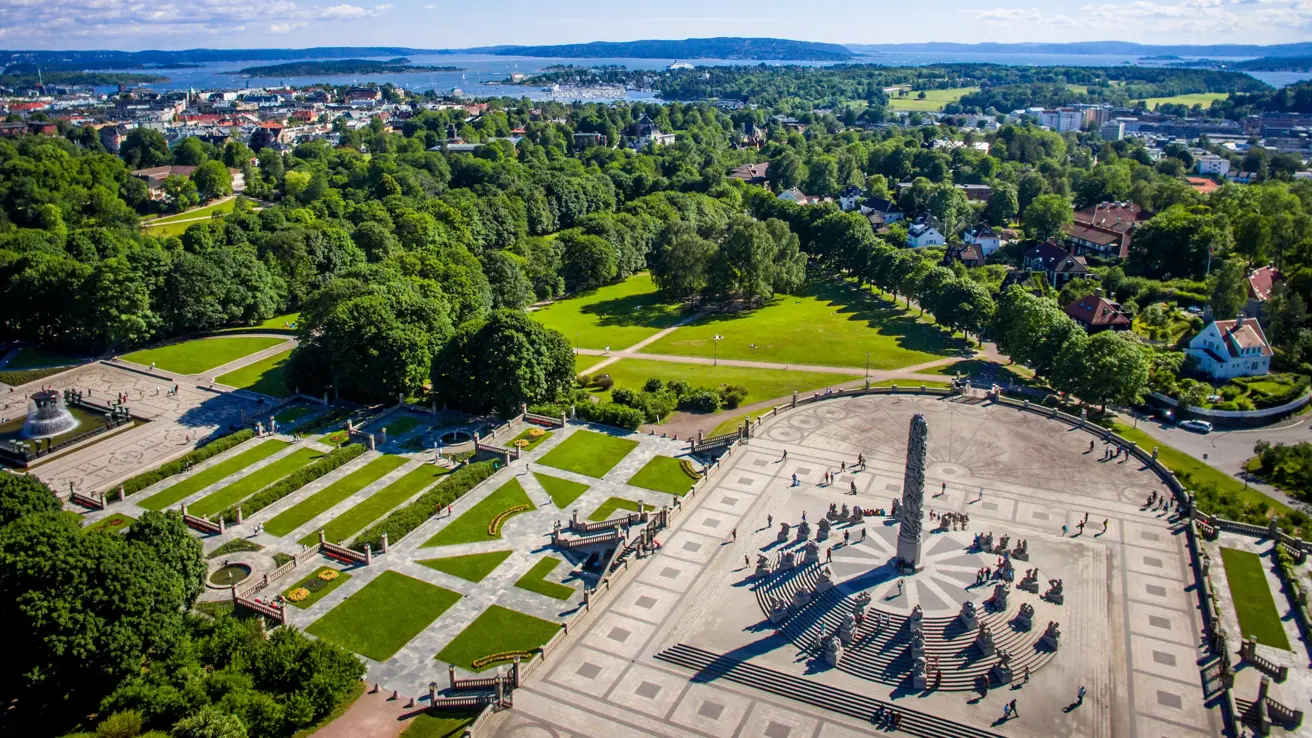 Monolith Statue photographed from the air, using a drone. 
In the horizon the Inner Oslofjord can be seen and the clear blue sky of June is in the background.

Monolith is a stone statue placed on "Monolith Plateau" in Vigeland Park in Oslo.  It consists of 121 figures. The sculpture is surrounded by a circular staircase with 36 groups of figures in granite arranged in rows up the stairs. The sculpture is carved out of a single granite block.