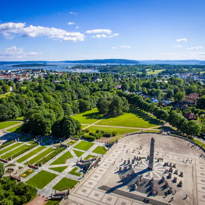 Monolith Statue photographed from the air, using a drone. 
In the horizon the Inner Oslofjord can be seen and the clear blue sky of June is in the background.

Monolith is a stone statue placed on "Monolith Plateau" in Vigeland Park in Oslo.  It consists of 121 figures. The sculpture is surrounded by a circular staircase with 36 groups of figures in granite arranged in rows up the stairs. The sculpture is carved out of a single granite block.