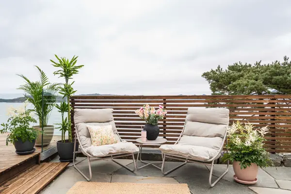 Terrasse med to hagestoler, bord og planter.