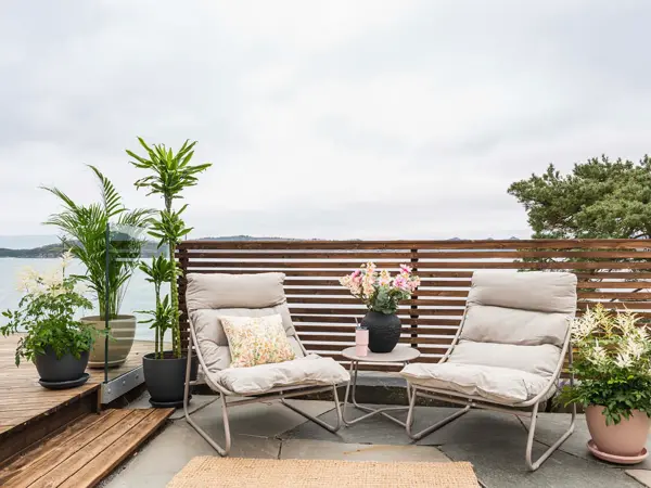 Terrasse med to hagestoler, bord og planter.