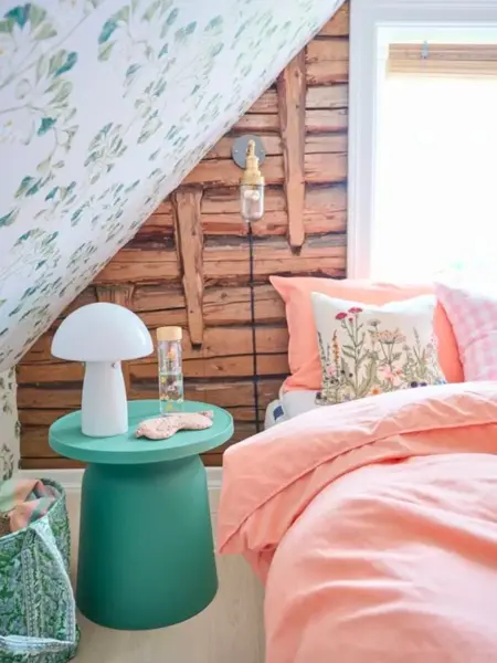 Interiørbilde fra soverom med ferskenfarget sengetøy på sengen.