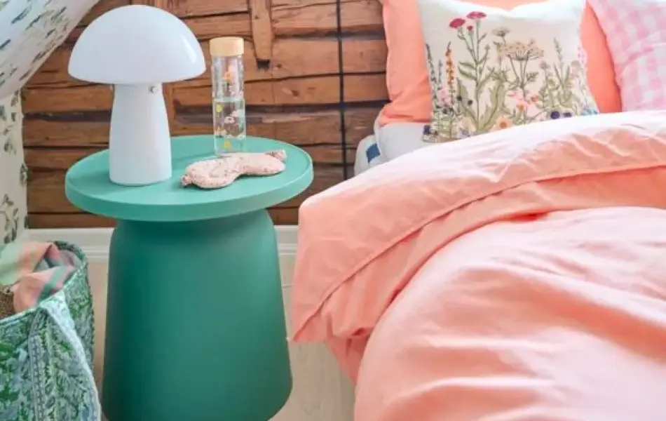 Interiørbilde fra soverom med ferskenfarget sengetøy på sengen.