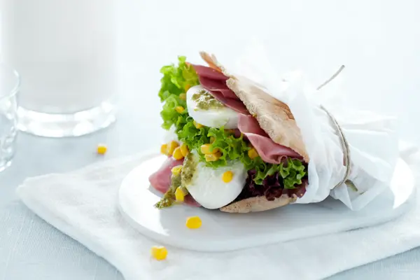 Et pitabrød fylt med mozzarella og skinke i en matpakkepapir