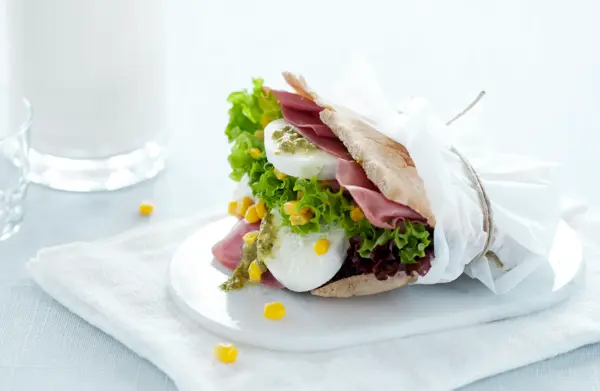 Et pitabrød fylt med mozzarella og skinke i en matpakkepapir