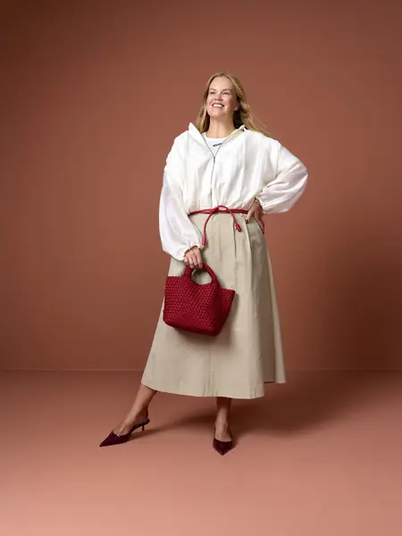 Elen med hvt skjorte, beige skjørt og røde sko og veske.