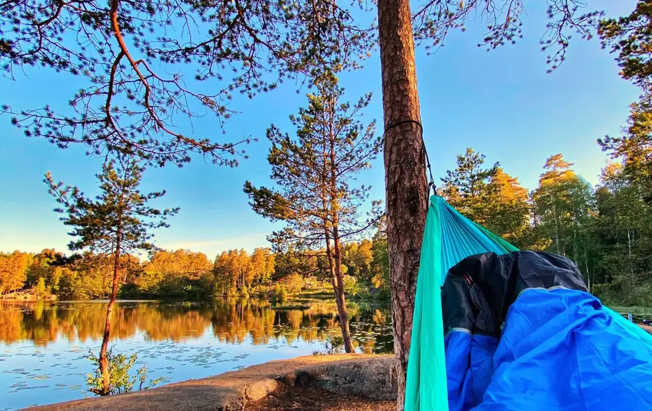 Utsnitt av hengekøye og utsikt over vann og natur