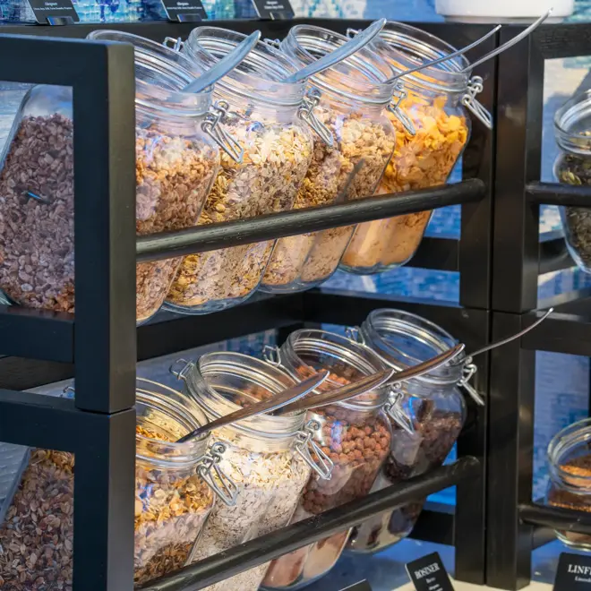 Nærbilde av krukker med granola og müsli i hylle på frokostbuffet ved Thon Hotel Skis frokostsal