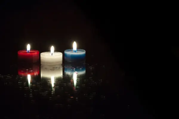 Nærbilde av telys i rødt, hvitt og blått på svart bakgrunn. Foto til artikkel om 17. mai-dekorasjoner.