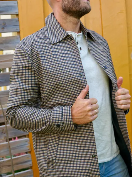 Mann med som holder en rutete jakke åpen