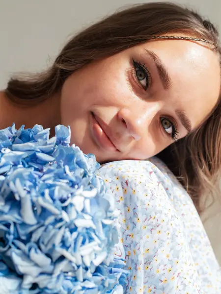 Nærbilde av jente med blå blomstrete kjole og blå blomst 