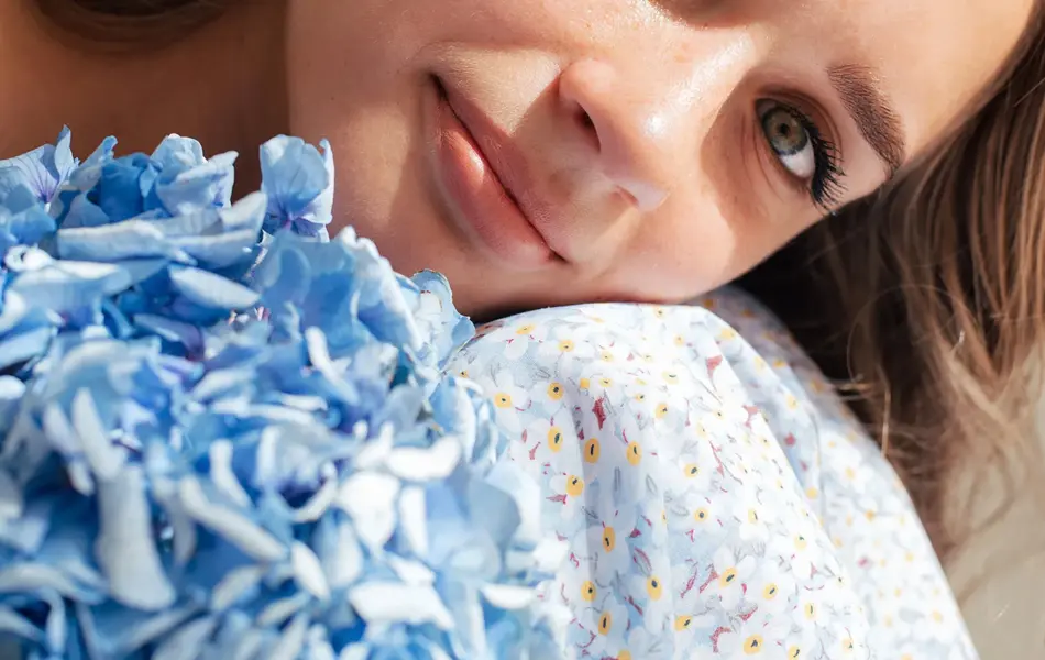 Nærbilde av jente med blå blomstrete kjole og blå blomst 