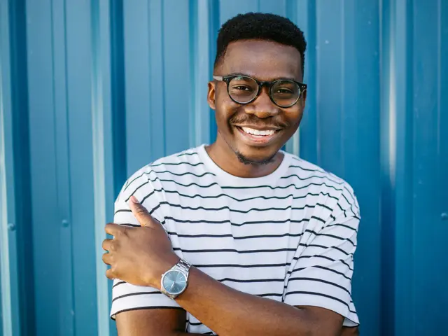 Mann med stripete t-skjorte og briller poserer foran blå vegg 