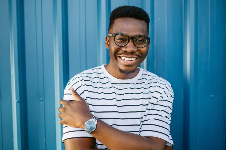 Mann med stripete t-skjorte og briller poserer foran blå vegg 