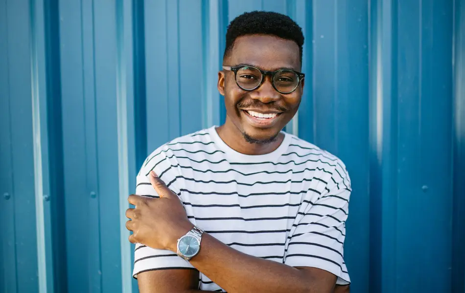 Mann med stripete t-skjorte og briller poserer foran blå vegg 