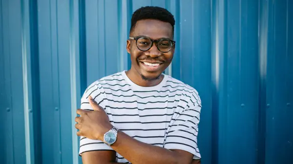 Mann med stripete t-skjorte og briller poserer foran blå vegg 