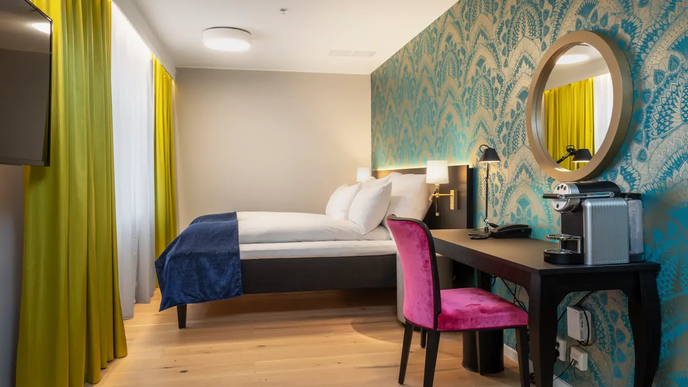 Skrivebord, rosa stol, vindu, gule gardiner, dobbeltseng