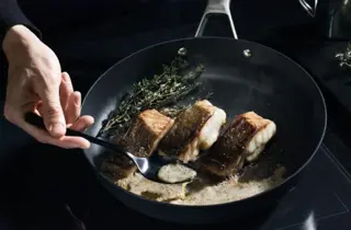 Stekepanne med stekt fisk og friske urter.