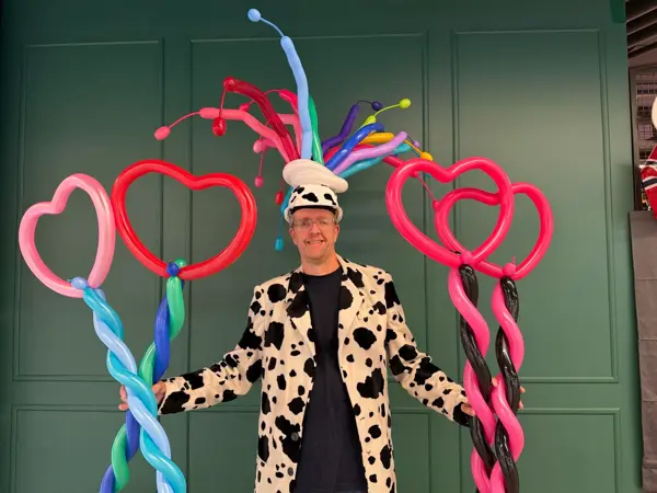 En mann med ballonghatt og hjerteballonger i hendene