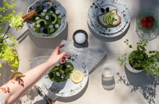 Et bord dekket til middag med en salat på bordet, og en hånd som strekker seg etter saltet i midten av bordet.