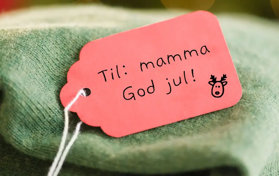 Grønn strikket genser med en rød lapp