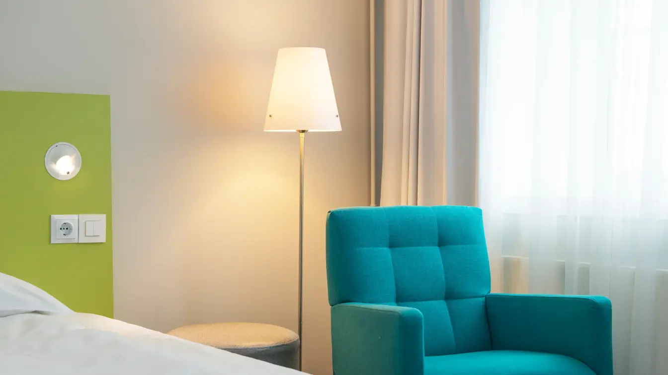 Nærbilde av turkis lenestol og limegrønt sengegavl på Standard Room Queen på Thon Hotel Trondheim. 