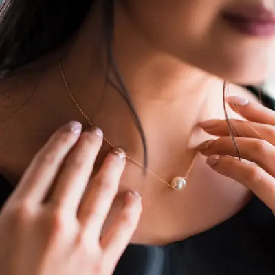 Young woman trying on neck an elegant pearl jewelry.Get dressed for the celebration